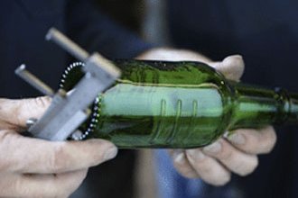 [Translate to Italienisch:] Ein Mann prüft die Glasflasche auf ihre Qualität. 
